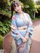 A woman in a blue kimono posing for a picture.