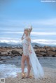 A woman in a white dress standing on a beach.