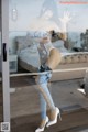 A woman in a white bodysuit and high heels standing in front of a glass door.