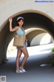 A woman standing in a tunnel holding a straw bag.