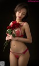 A woman in a red lingerie holding a bunch of roses.