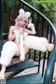 A woman in a white fur coat sitting on a set of stairs.