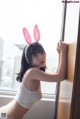 A woman in bunny ears leaning against a window.