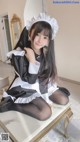 A woman in a maid outfit sitting on a table.