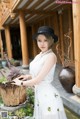 A woman in a white dress and black hat posing for a picture.