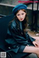 A woman sitting on a bench wearing a blue beret.