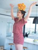 A woman in a red and white polka dot dress holding a basket of oranges.