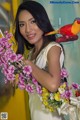 A woman holding a bunch of flowers and a bird.