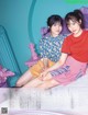 A couple of young women sitting on top of a bed.